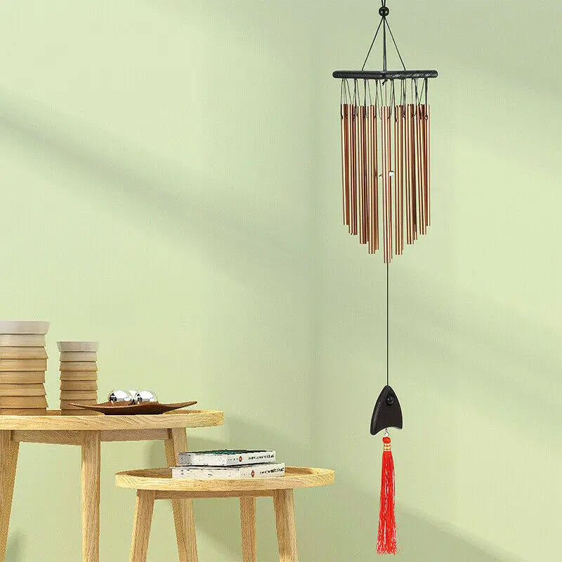 Wooden tables with stacked books and bowls on the left, and a wind chime with red tassel hanging on the right against a soft green wall.