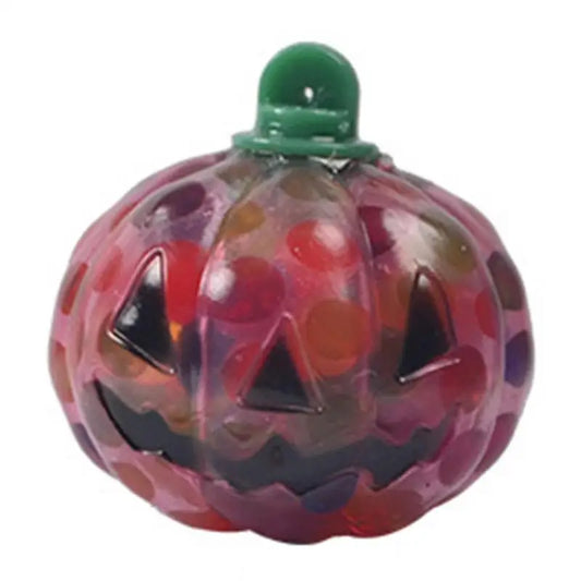 Colorful glass pumpkin with a smiling jack-o'-lantern face and a green stem on top. The surface is dotted with various bright colors, enhancing its festive appearance.