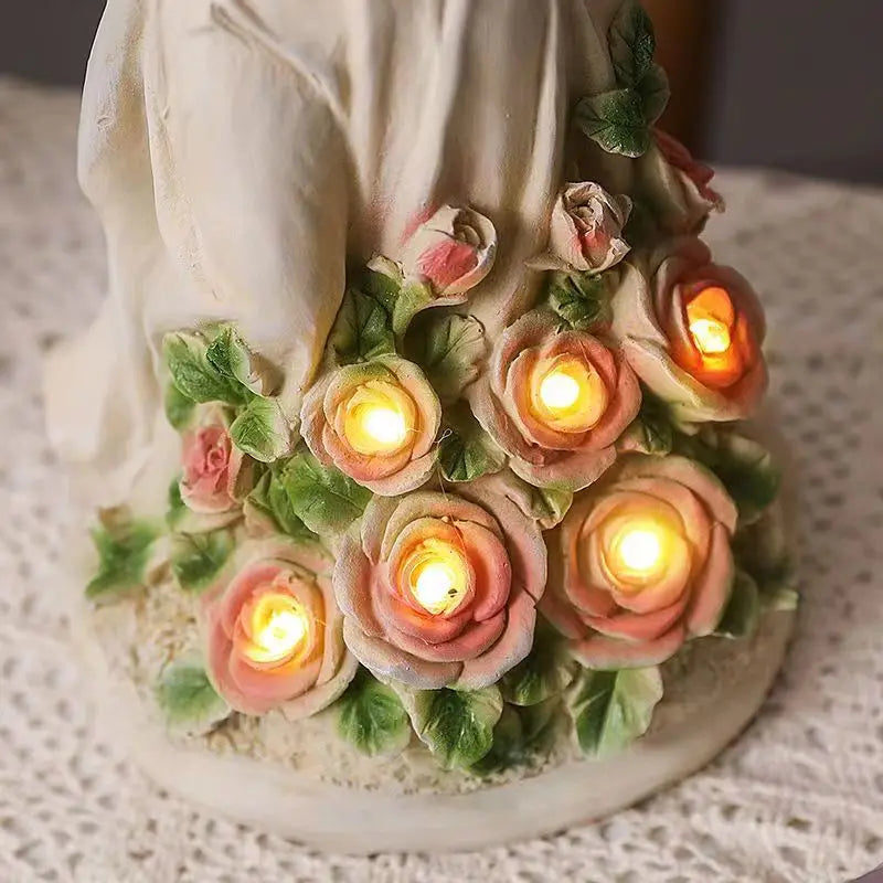 Ivory figurine adorned with glowing pink roses and green leaves, set on a lace tablecloth. Each rose is illuminated by a small light, creating a warm, inviting glow.