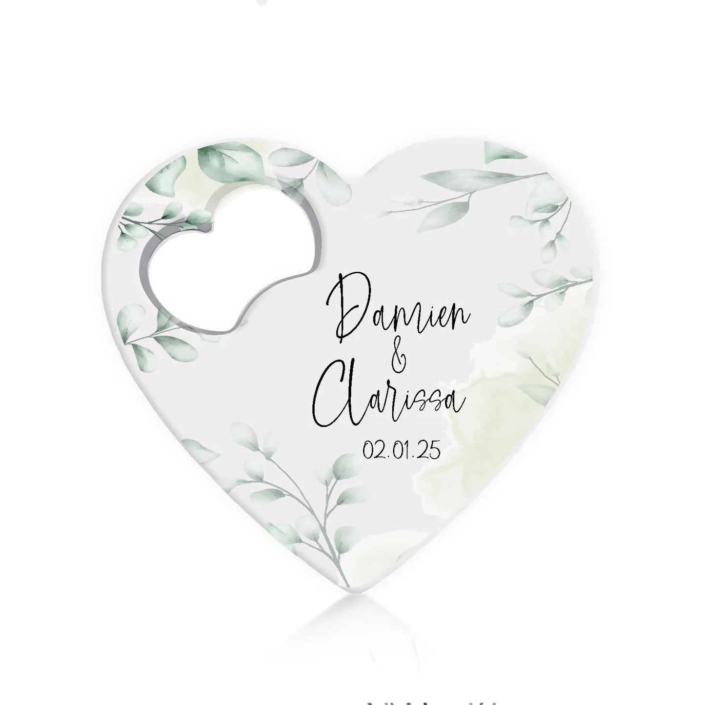 Heart-shaped save-the-date magnet with green leaf design. Text reads "Dannie & Clarissa" above "02.01.25" in elegant script. A small heart cutout is on the left side.