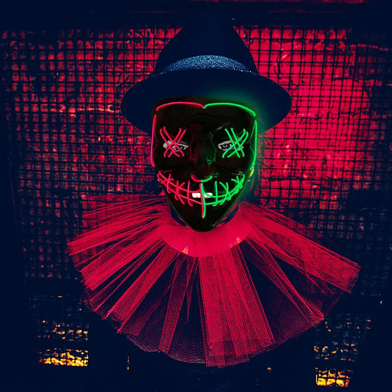 Person in a dark setting wears a glowing neon mask with cross-eyed design and stitched smile, topped with a hat and illuminated by red lights.