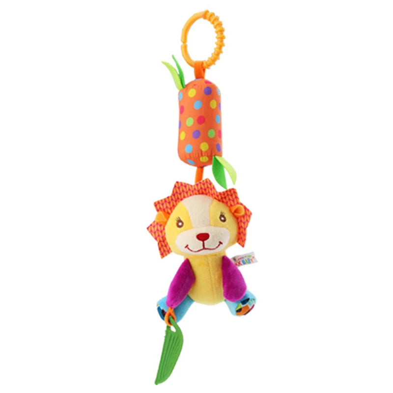 Colorful plush lion toy with a smiling face, purple paws, and a textured green teether. It hangs from an orange ring, attached to a polka-dotted cylinder with fabric leaves.