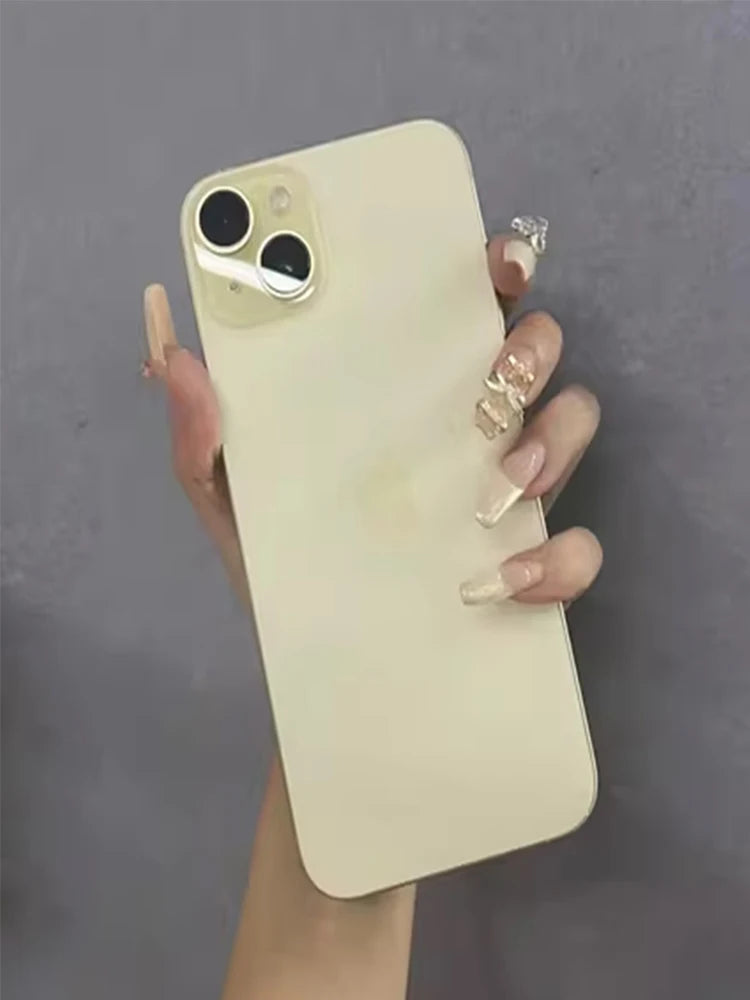 A hand with long, decorated nails holds a cream-colored smartphone with a dual-camera setup, against a gray background.
