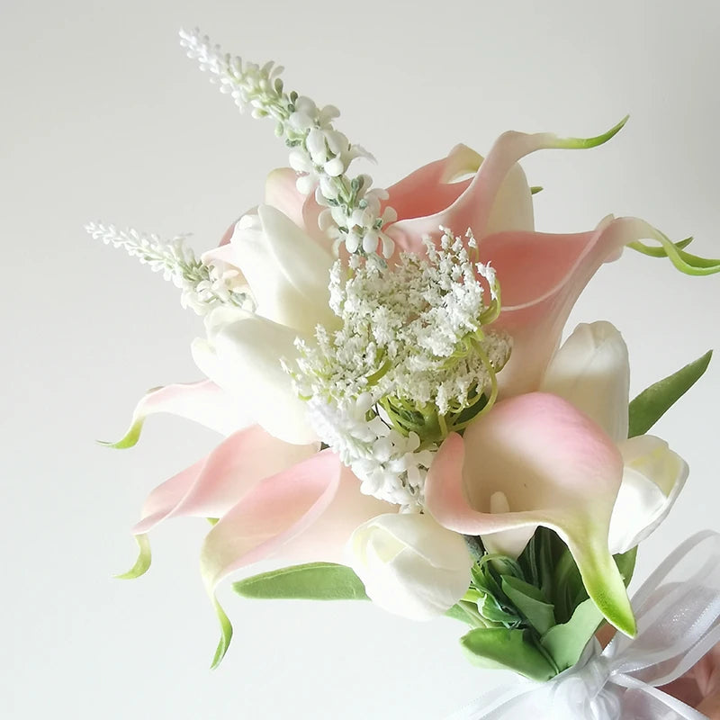 Bouquet with pink and white calla lilies and white veronica flowers, accented with Queen Anne's lace, wrapped in a white ribbon against a light background.