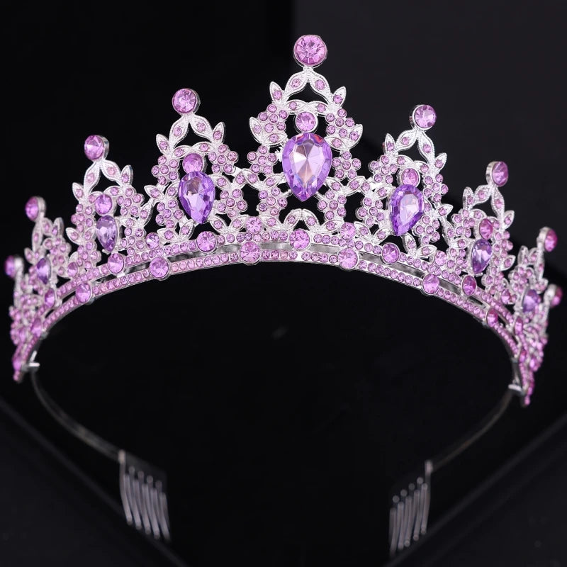 A silver tiara adorned with intricate designs and multiple purple gemstones, including large teardrop shapes. The background is black, emphasizing the tiara's sparkle.