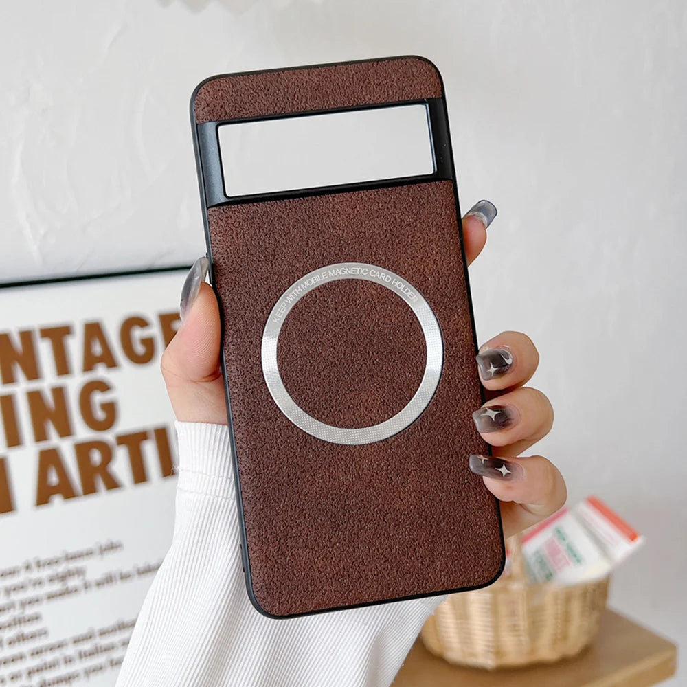 Hand holding a brown phone case with a circular magnetic card holder and clear window at the top. The background features a framed quote and a wicker basket.