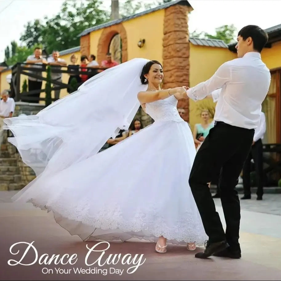 A bride and groom joyfully dance outdoors, with her white dress swirling elegantly. Guests watch from behind. The text reads "Dance Away On Your Wedding Day."