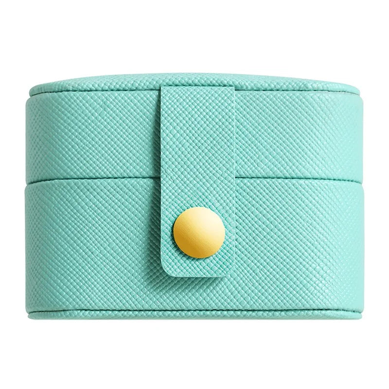 Compact teal travel jewelry organizer with a textured surface, featuring a snap closure with a gold-tone button. Ideal for keeping jewelry safe and tidy on the go.