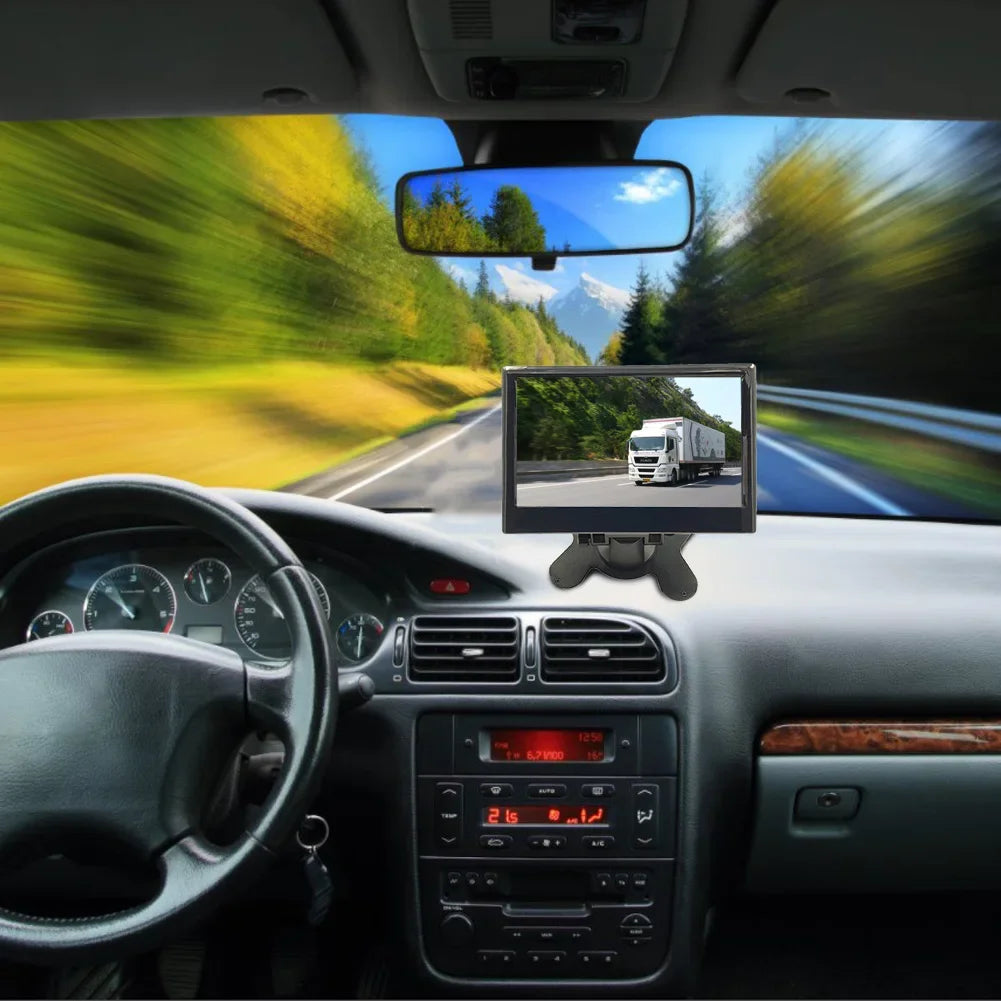 Car interior view with a GPS screen displaying a truck on a winding road. The background shows a blurred scenic drive with green trees and blue sky, emphasizing speed.