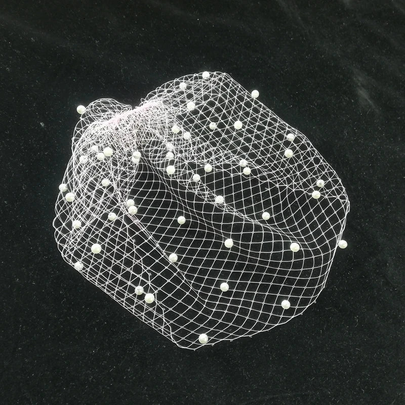 Delicate white net with evenly spaced small pearls, arranged on a black surface. The netting appears airy and light, forming a gentle, rounded shape.