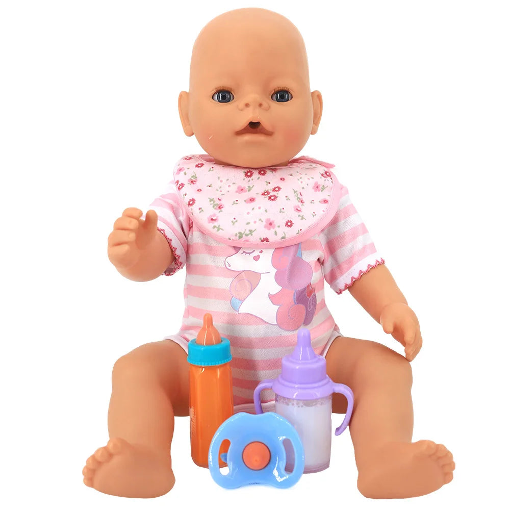 A doll wearing a striped pink unicorn outfit and floral bib sits with an orange bottle, a purple-handled bottle, and a blue pacifier placed in front of it.