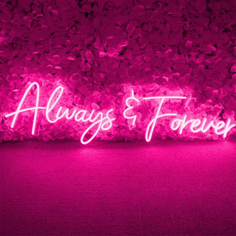 Pink neon sign reading "Always & Forever" against a lush wall of pink flowers, creating a romantic and vibrant ambiance.