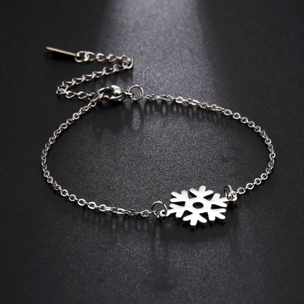 Silver bracelet with a delicate chain and central snowflake charm, displayed on a dark background. The bracelet features an adjustable clasp for varying wrist sizes.