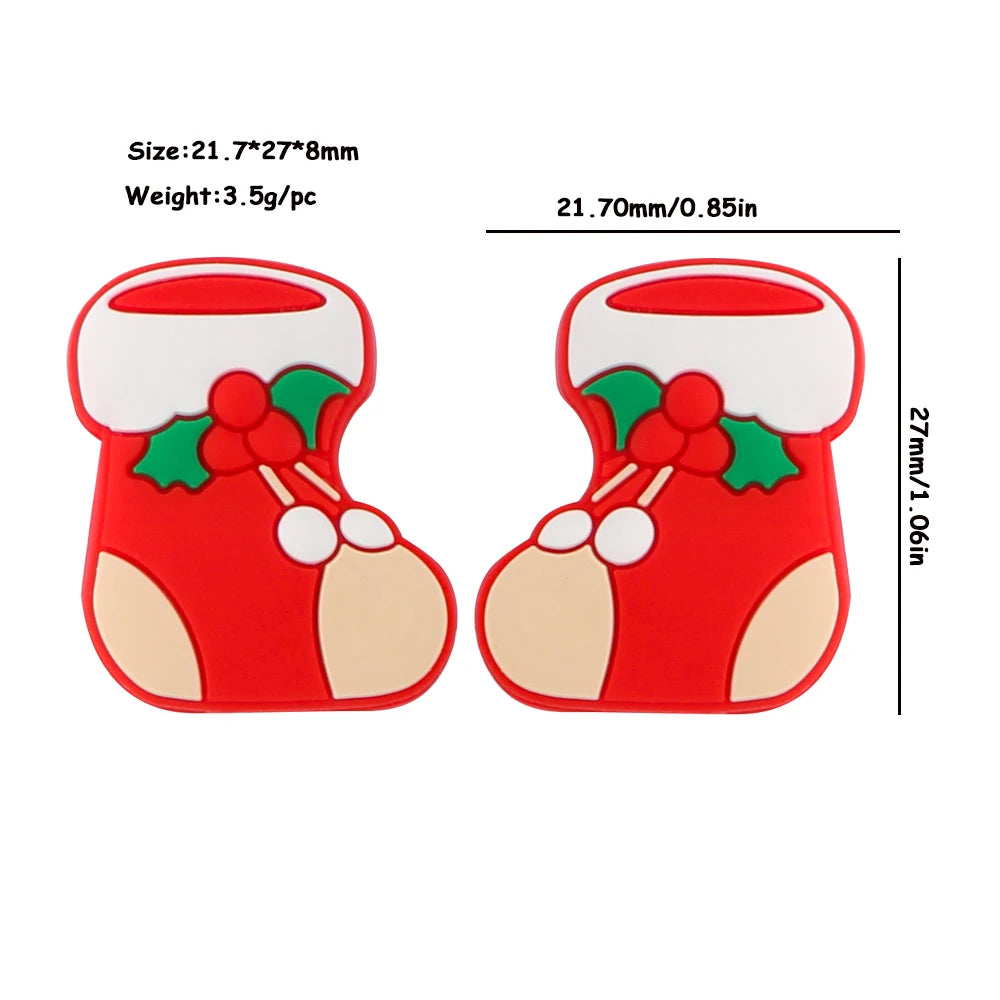 Two red Christmas stocking-shaped buttons with white cuffs and holly details. Each measures 21.7mm wide, 27mm tall, and weighs 3.5g.