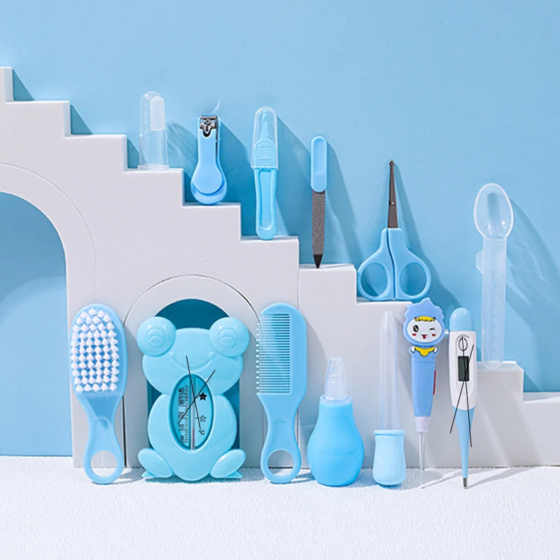 A collection of baby grooming items, including a thermometer, comb, nail clippers, scissors, nasal aspirator, and brush, all in shades of blue, arranged on a white step-like display.