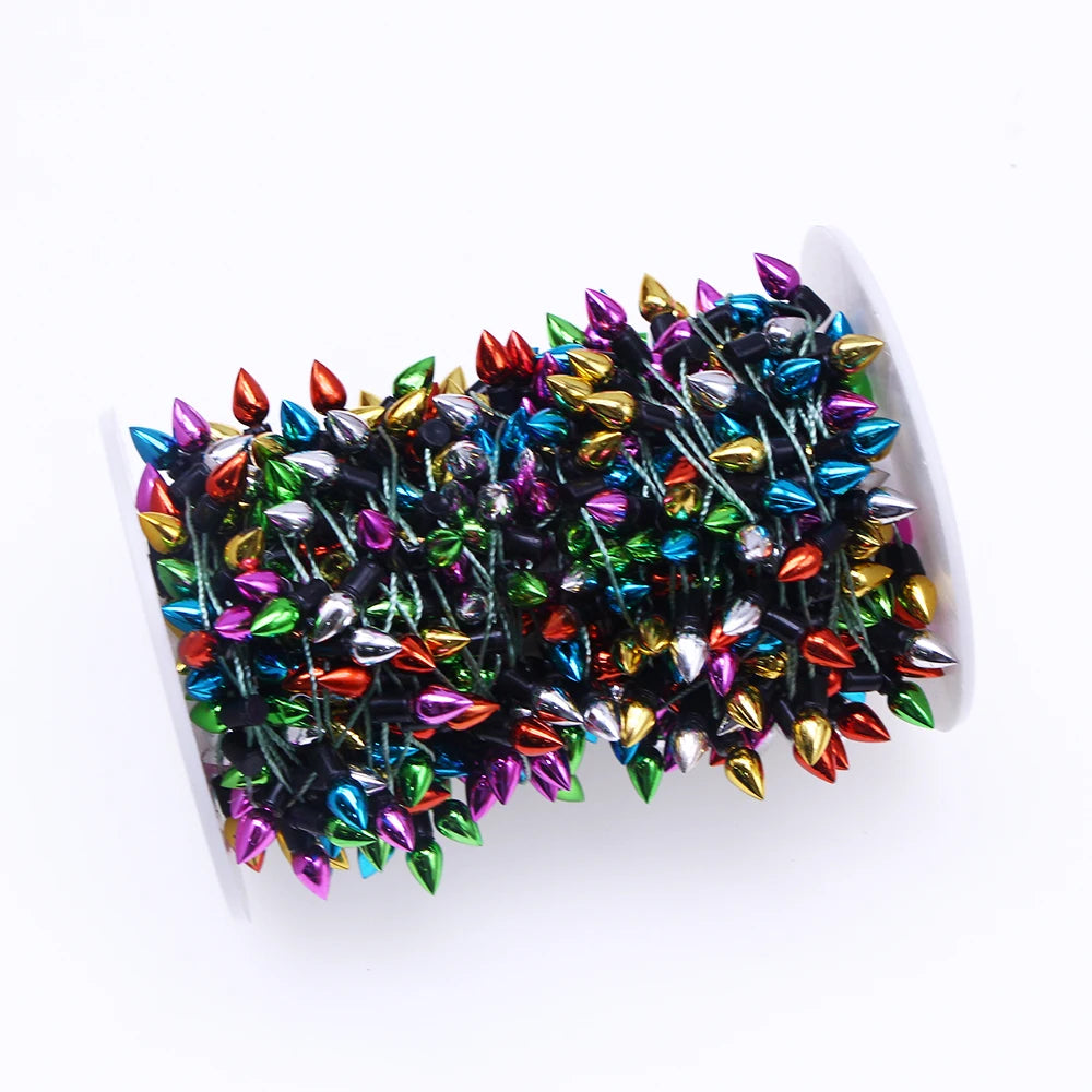 Spool of colorful, metallic string lights with small teardrop-shaped bulbs in various colors, tightly wound around a white reel.
