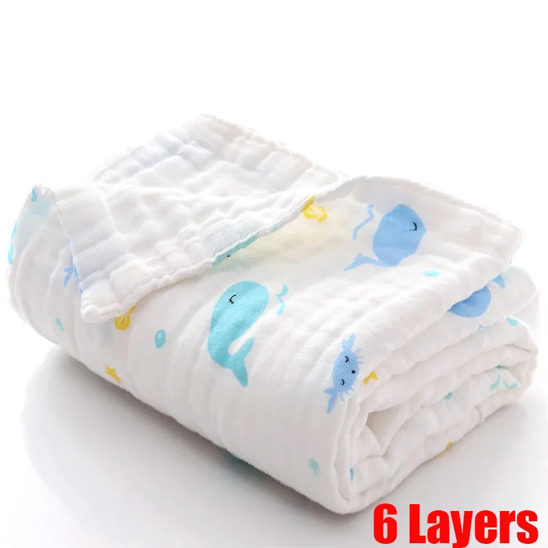 A soft, 6-layered white baby blanket featuring cute blue and yellow whale illustrations, folded neatly on a white background. Large red text reads "6 Layers."