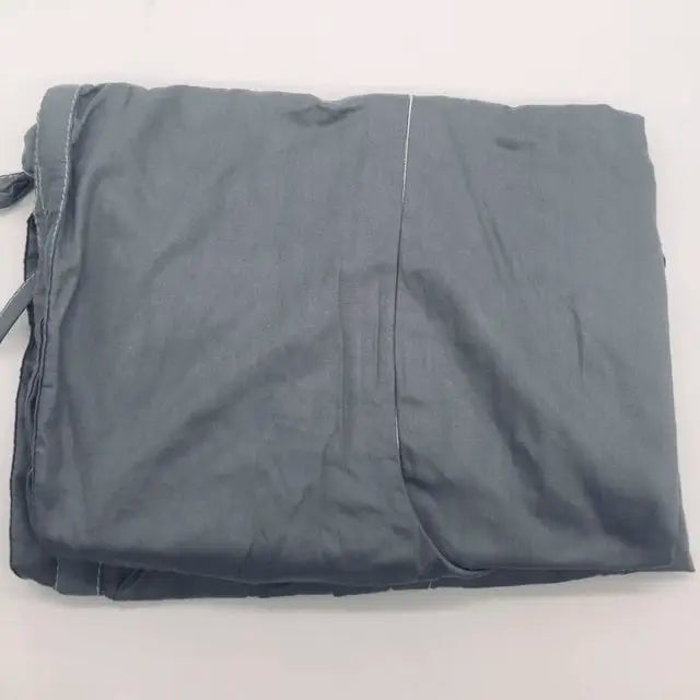 A neatly folded gray fabric cover with visible stitching lines and a tie on one side, laying on a light surface.