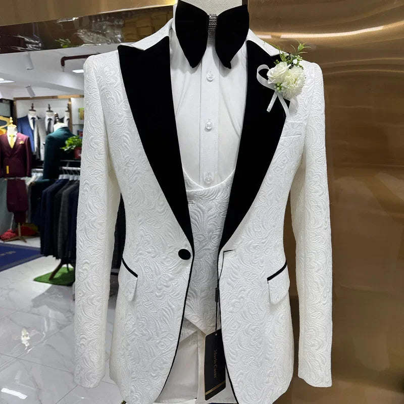 White textured suit jacket with black lapels on a mannequin, paired with a white shirt and vest. A black bow tie and white boutonniere complete the look.