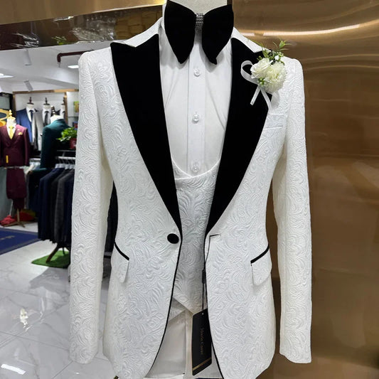 White textured suit jacket with black lapels on a mannequin, paired with a white shirt and vest. A black bow tie and white boutonniere complete the look.