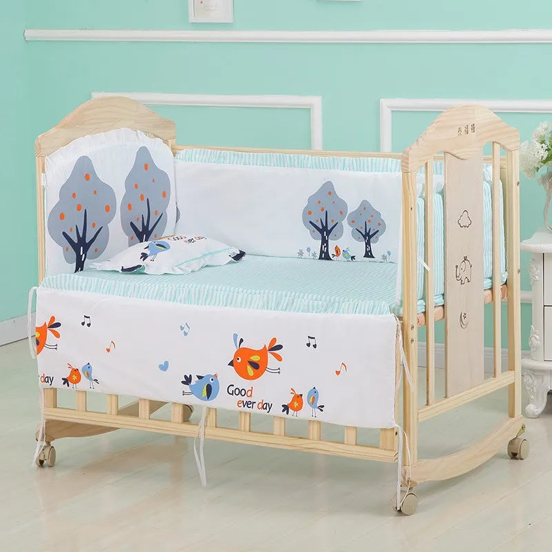 A wooden baby crib with decorative blue and white bedding featuring playful bird and tree designs. The crib has wheels, and the room has mint-green walls.