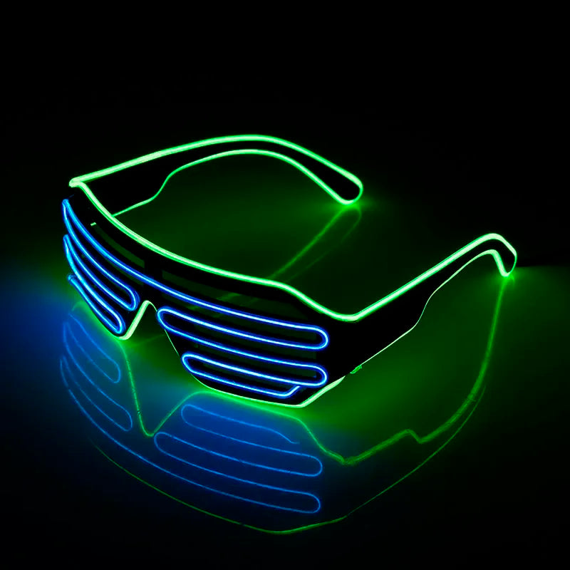 Neon green and blue shutter glasses glow brightly in the dark. The glasses feature horizontal bars in the lenses and reflect light on the surface below.