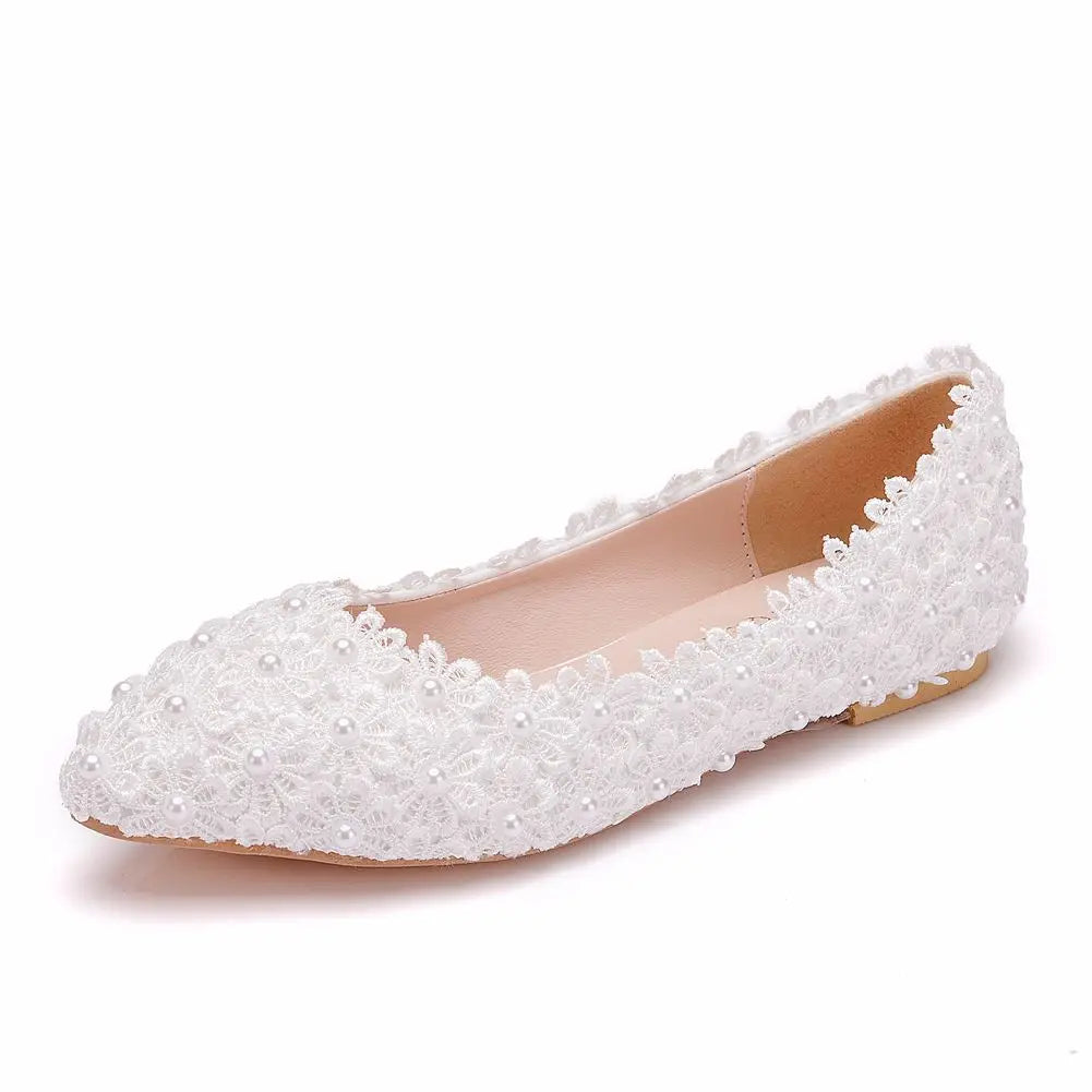 White lace flat shoe adorned with delicate floral embroidery and small pearl accents on a plain background.