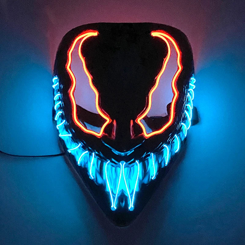 A glowing mask with red outlines on the eyes and blue teeth, resembling a sinister grin, illuminated against a dark background.