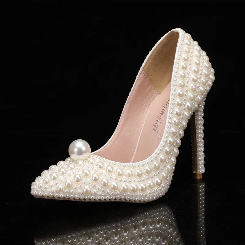 Elegant high-heeled shoe adorned with ivory pearls, featuring a prominent pearl on the pointed toe. Its delicate craftsmanship showcases sophistication and style.