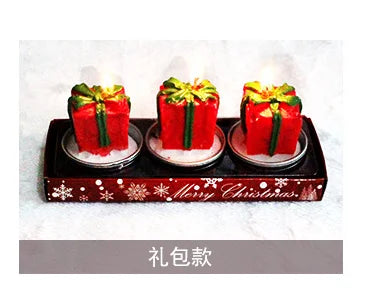 Three red gift-shaped candles with green ribbon designs on a tray with "Merry Christmas" text. Snowflake decorations and Chinese characters are visible below.