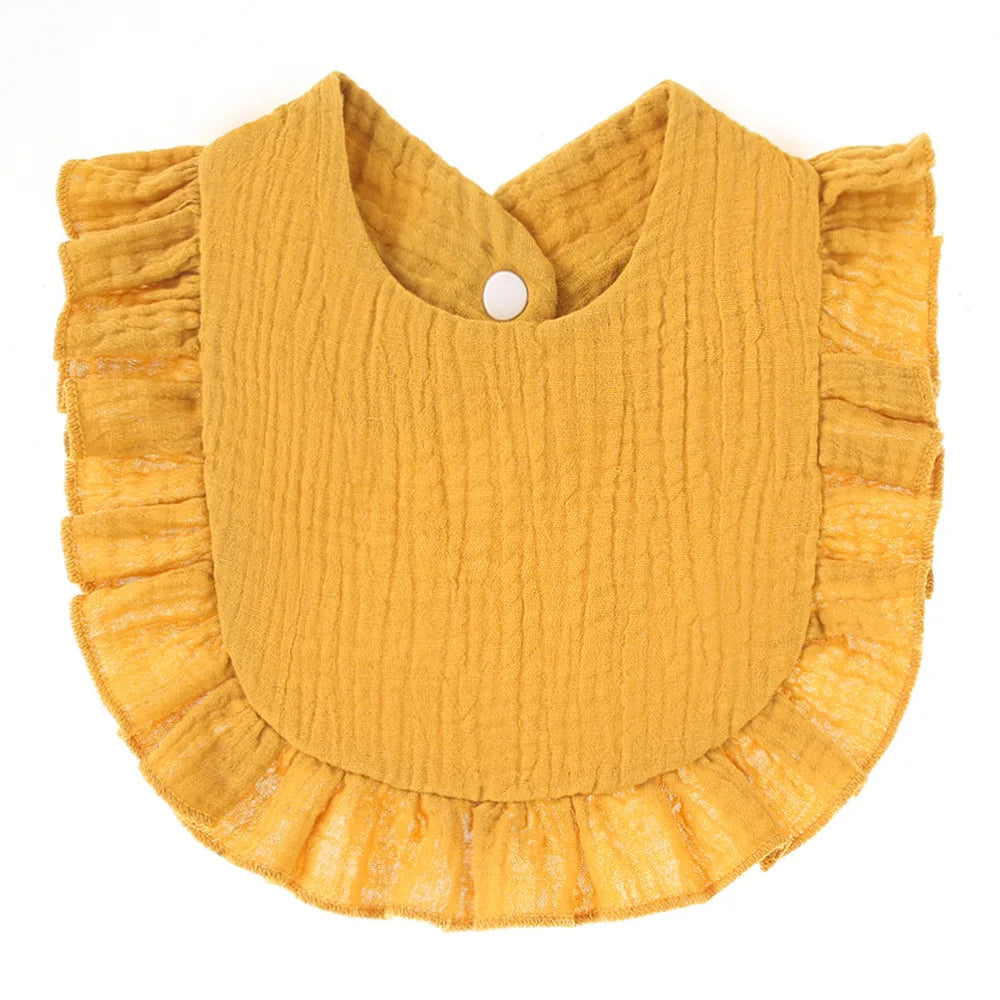 Mustard-colored baby bib with a crinkled texture, featuring a ruffled edge and a white snap closure at the top.