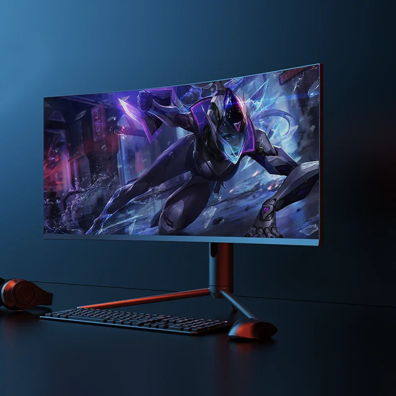 Ultra-wide monitor displaying a futuristic armored character in an action pose. Set on a sleek desk with a keyboard, mouse, and headphones, all against a dark background.