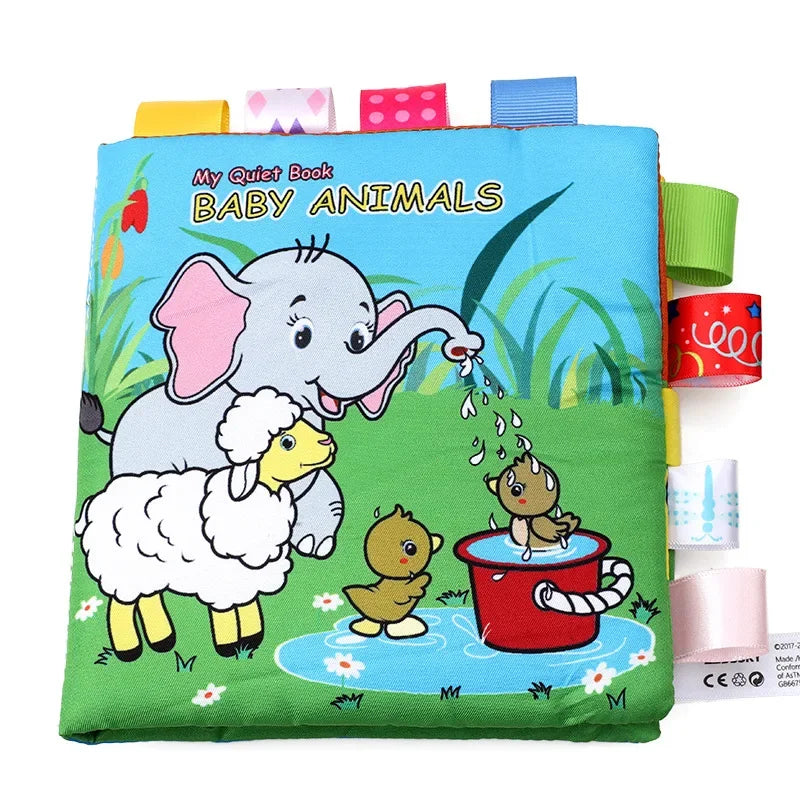 Children's cloth book cover titled "My Quiet Book: Baby Animals" showing an elephant, lamb, and ducklings playing near water with colorful ribbons attached.