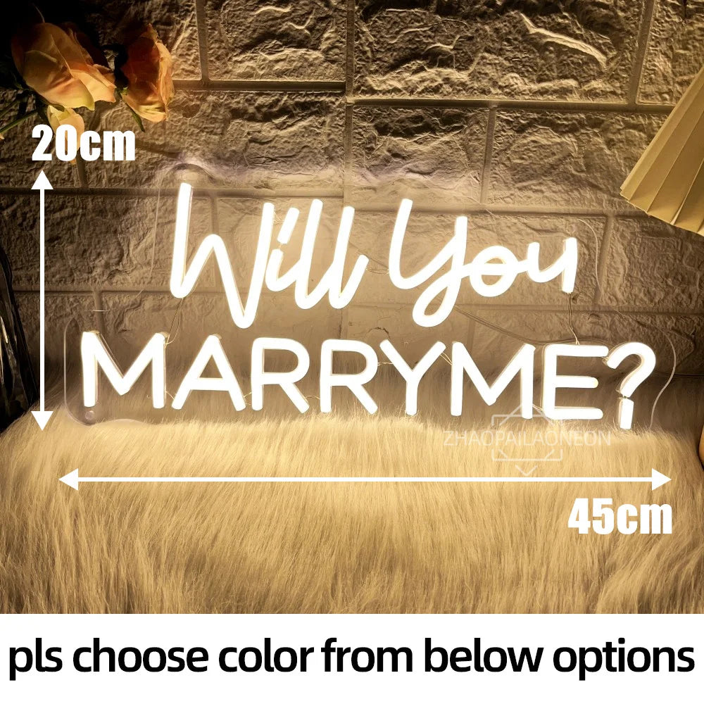 Neon sign reading "Will You Marry Me?" on a textured wall. Text measures 20cm high and 45cm wide. Yellow roses and lamp are visible. Text below reads "pls choose color from below options."
