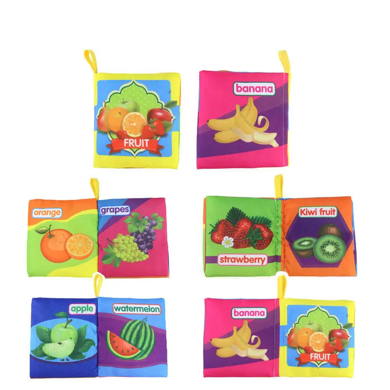 Colorful fabric books with fruit illustrations: apple, watermelon, banana, orange, grapes, strawberry, and kiwi. Each book has vibrant pages and yellow tabs for easy handling.