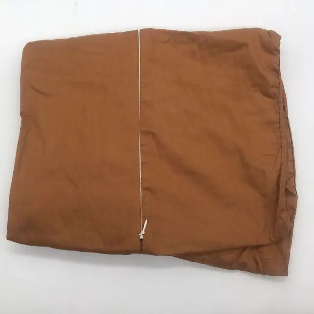 A folded brown fabric duvet cover with a visible zipper running vertically down the center, placed on a plain white surface.