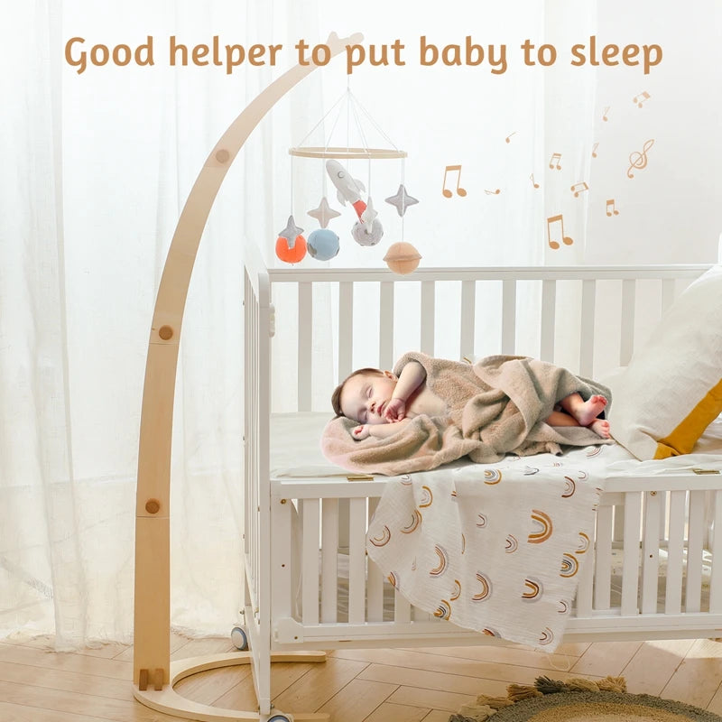 A baby sleeps peacefully in a white crib with a soft blanket. A curved wooden mobile with colorful toys hangs above. Text reads, "Good helper to put baby to sleep."