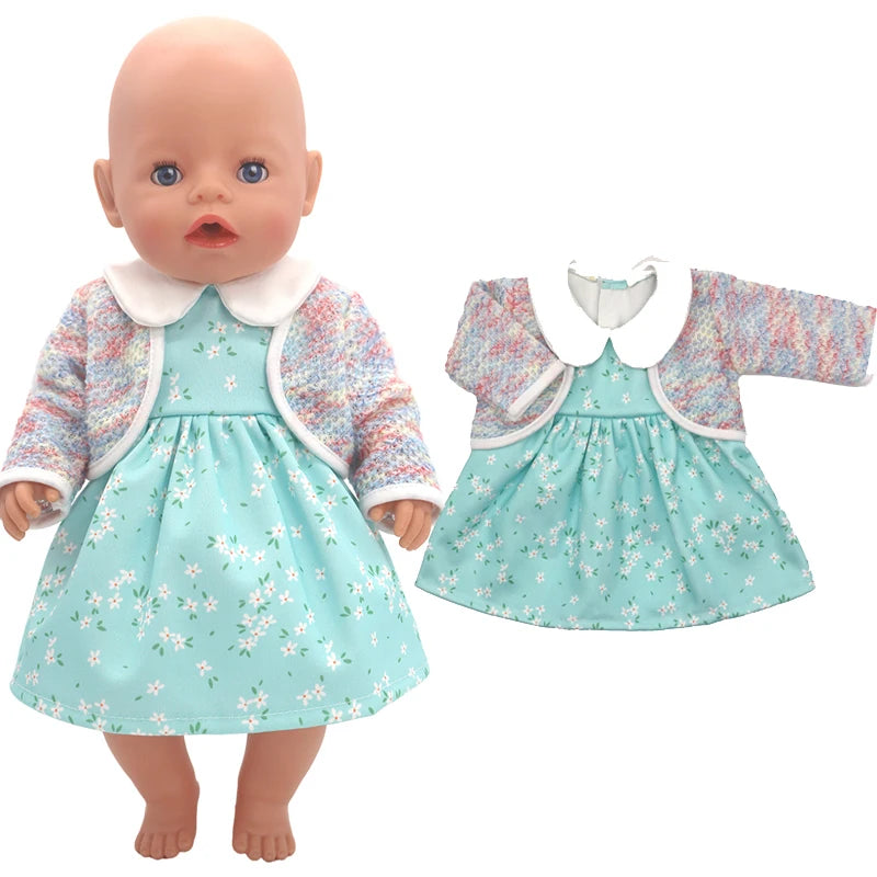 A bald baby doll dressed in a floral turquoise dress with a white collar and a pastel rainbow cardigan. An identical outfit is displayed beside it for comparison.
