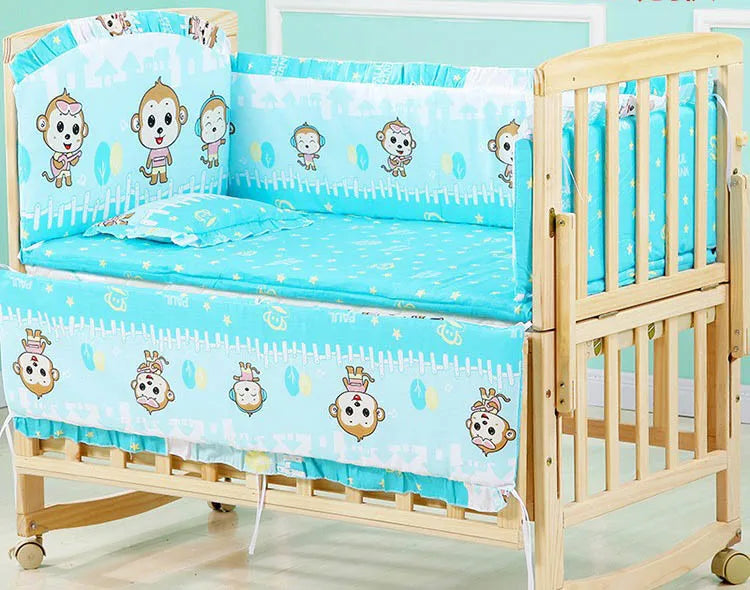 Wooden baby crib with turquoise bedding adorned with cartoon monkeys. The bedding set includes bumpers and a small pillow, creating a cheerful and cozy atmosphere.