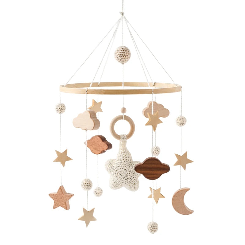 A wooden baby mobile featuring stars, clouds, and a crescent moon hangs from strings. Crocheted and wooden textures blend in a neutral color scheme, creating a calming nursery decor.