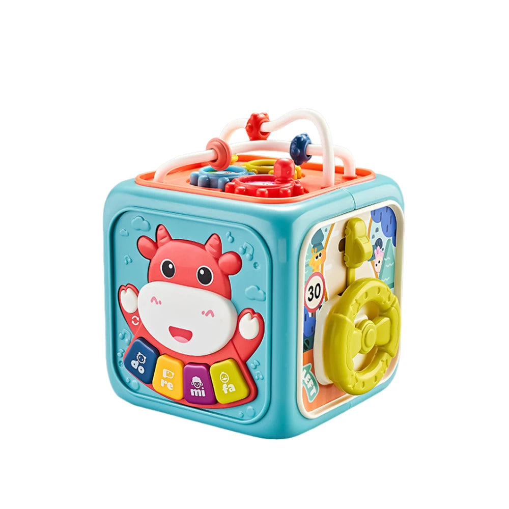 Colorful children's activity cube with musical buttons, a cartoon cow design, gears, beads, and a yellow steering wheel, encouraging sensory and motor skills development.