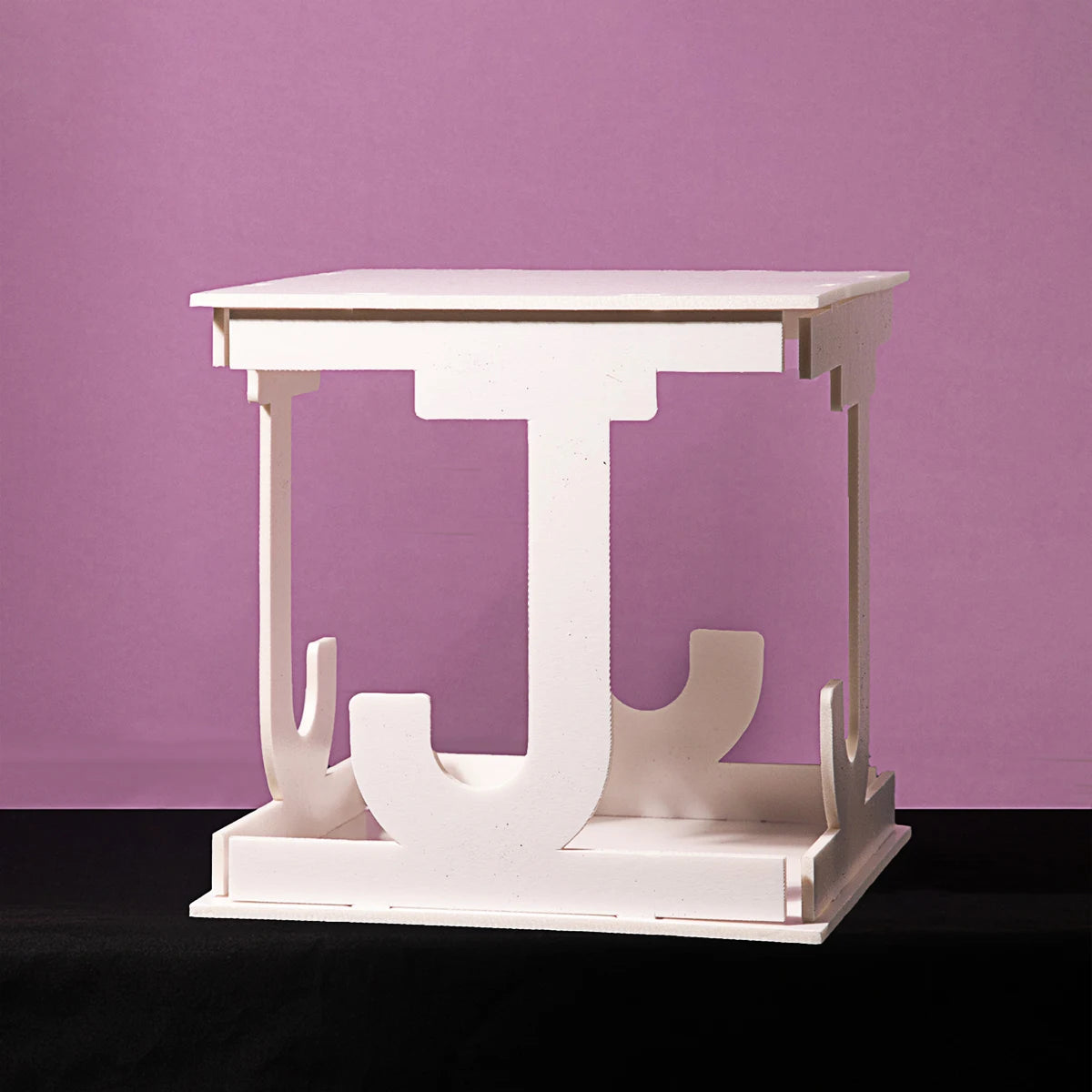 White square table with J-shaped supports on a black surface, set against a purple background.