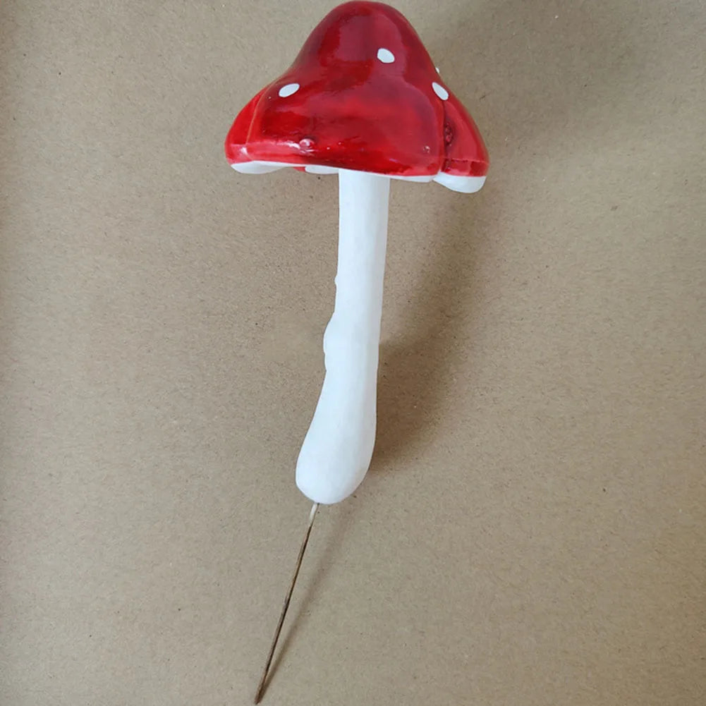 Red and white mushroom figurine with a pin stem on a beige background.