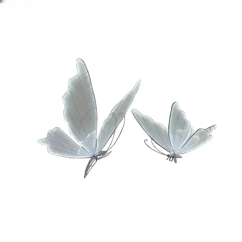 Two delicate, translucent white butterflies with fine, intricate wings appear against a plain white background, creating a minimalist and ethereal composition.