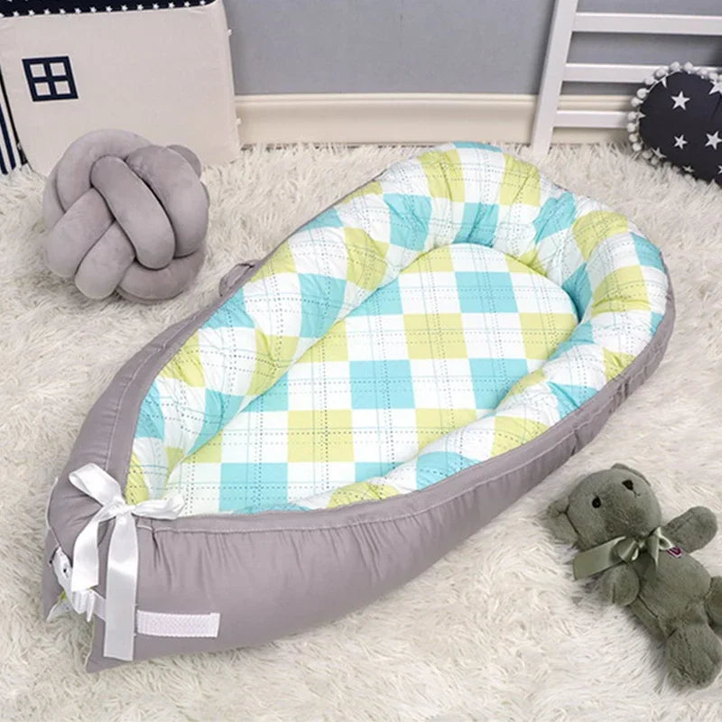 Cozy infant nest with plaid pattern in blue and green, set on a soft, cream rug. Nearby are a plush, knotted pillow and gray teddy bear with a bowtie.