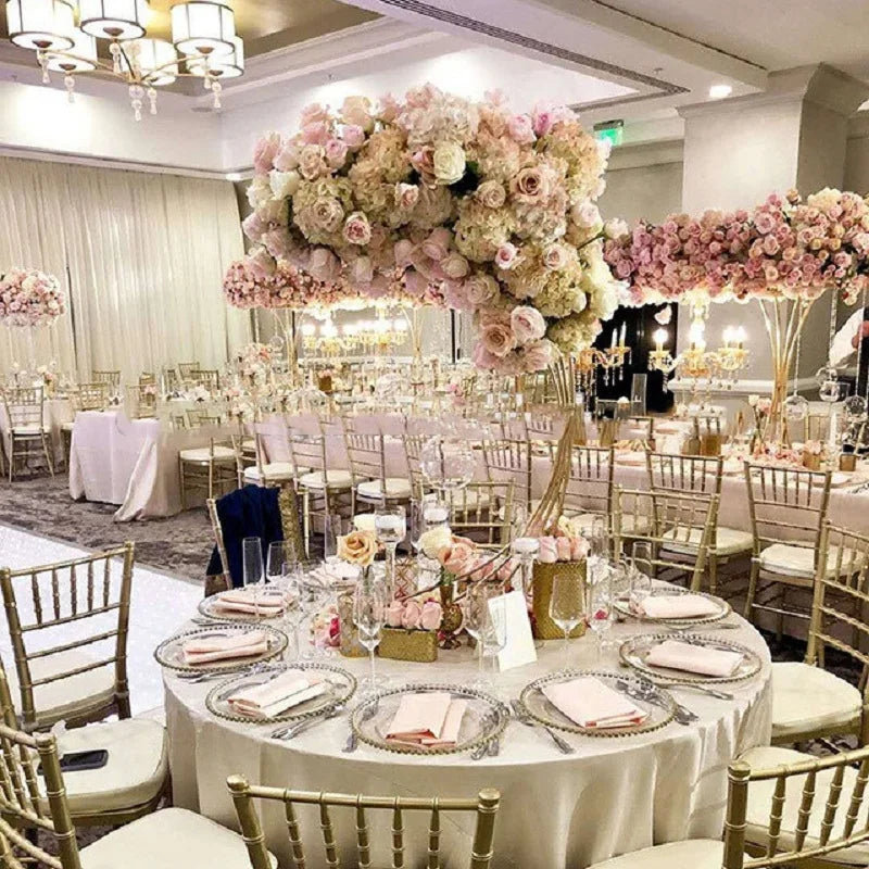 Elegant wedding reception with tables adorned with pink floral centerpieces, gold chairs, and soft lighting, creating a romantic, luxurious atmosphere.