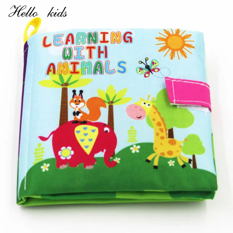 Children's fabric book titled "Learning with Animals" showing colorful illustrations of a giraffe, elephant, squirrel, and butterfly against a sunny, grassy backdrop.