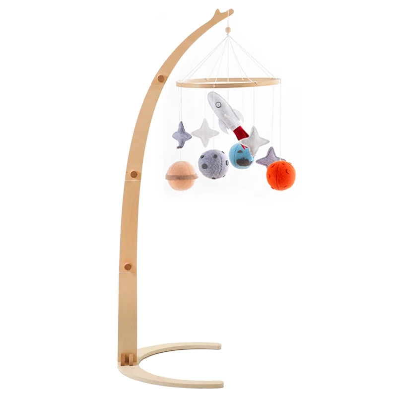 Wooden baby mobile featuring a space theme, with felt planets, stars, and a rocket, hanging from a curved wooden frame.
