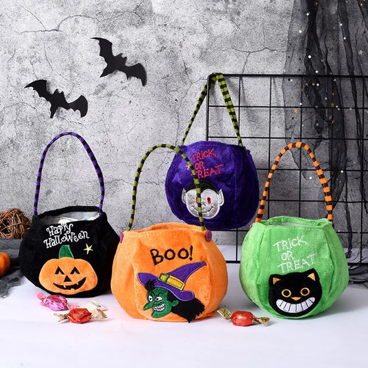 Four colorful Halloween treat bags with handles, featuring designs of a pumpkin, witch, vampire, and cat. Background includes bats on a textured wall and scattered candies.
