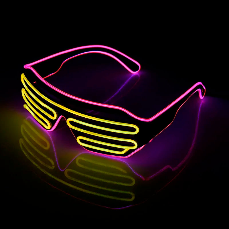 Neon LED glasses featuring bright pink frames and yellow slatted lenses, glowing vividly against a dark background, casting colorful reflections below.
